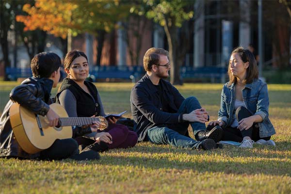 Students outdoors sitting in lawn of central campus