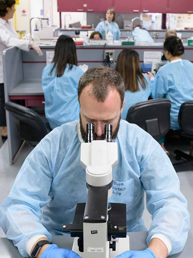 Medical lab student looking through a microscope.